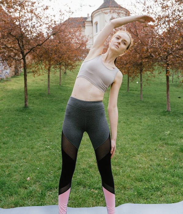 Woman in a calm yoga pose on a lilac background.